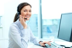 Señorita frente a pantalla con audífonos y micrófono, brindando servicio al cliente