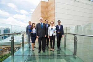 Grupo de ejecutivos de avanzada edad y jóvenes caminando sobre un puente de vidrio, quieren demostrar continuidad empresarial a través de las generaciones